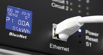 Ein Ethernet-Kabel ist in einen Anschluss an einem BlueNet-Gerät mit Display und Statusanzeigen eingesteckt.